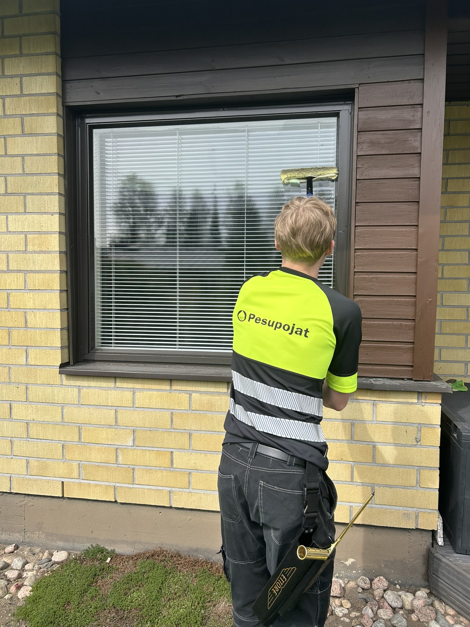 Pesupojat-työntekijä pesee talon ikkunaa