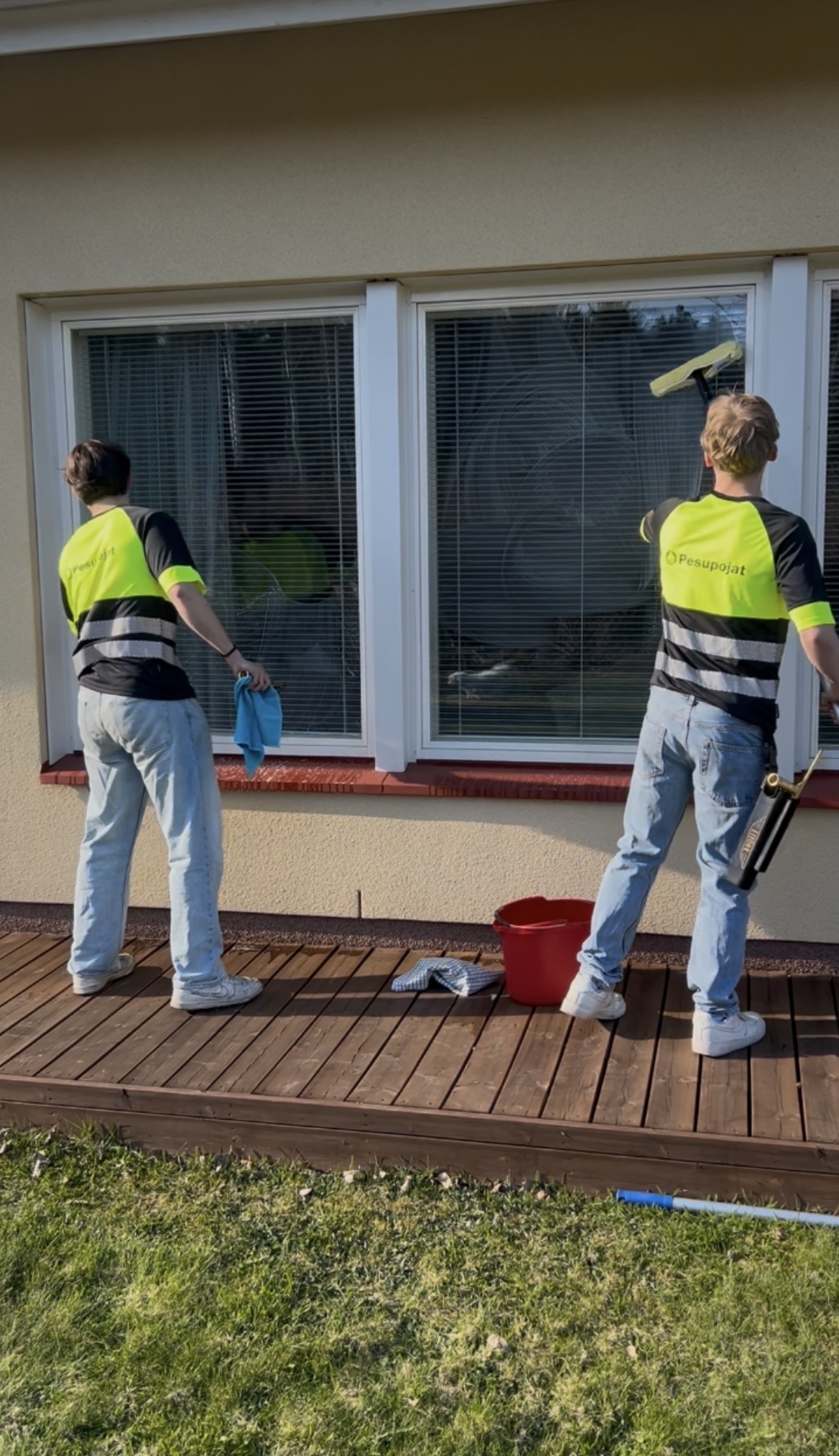 Kaksi pesupoikaa pesemässä talon ikkunoita